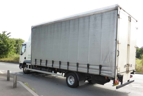 rigid truck with side guard between cab and rear wheels