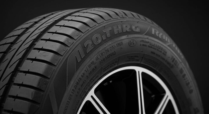 A close-up of a high-performance tire, showcasing its detailed tread pattern and sidewall markings. The embossed text on the sidewall includes tire specifications, indicating durability and road grip.