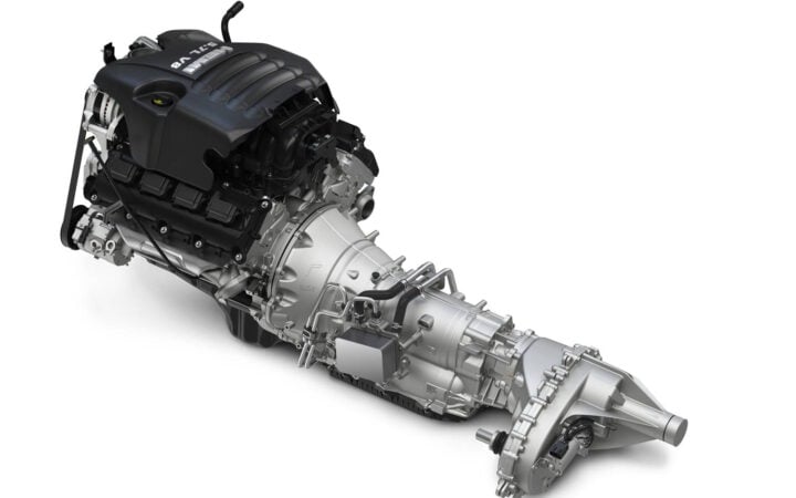 A high-resolution rendering of a powerful V8 engine connected to an advanced transmission system. The drivetrain assembly showcases precision engineering, with visible components including the engine block, transmission housing, and transfer case.
